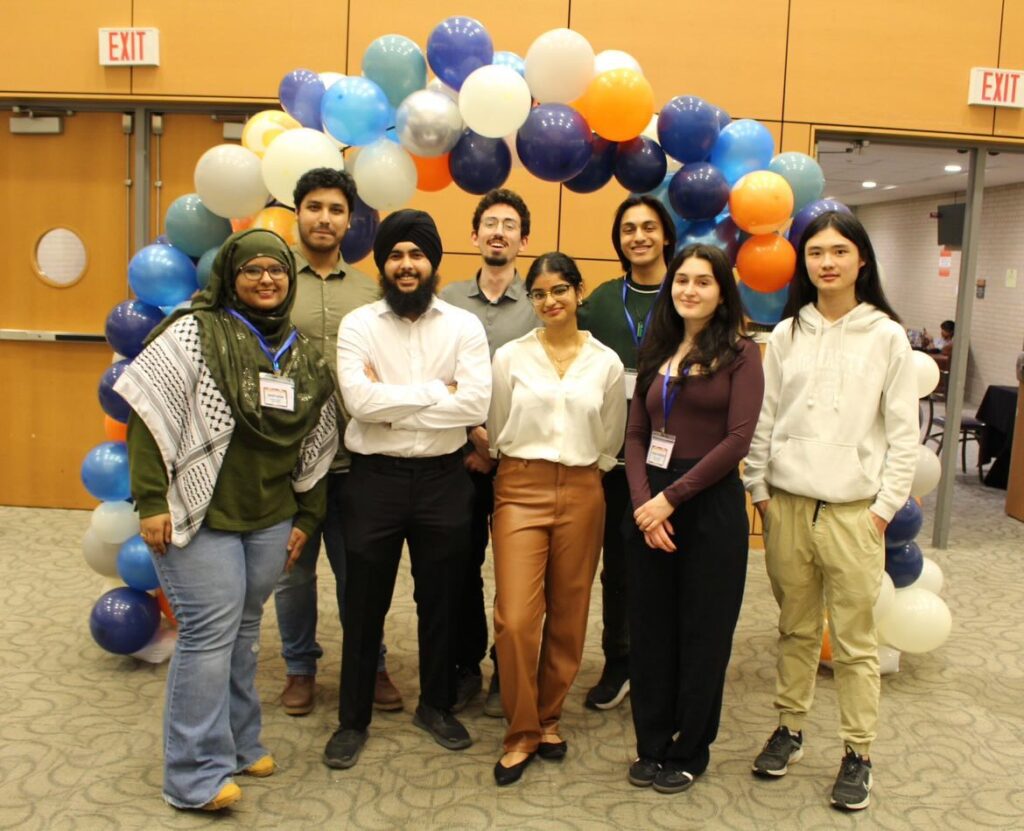 a group of students posing in front of a balloon arch. 