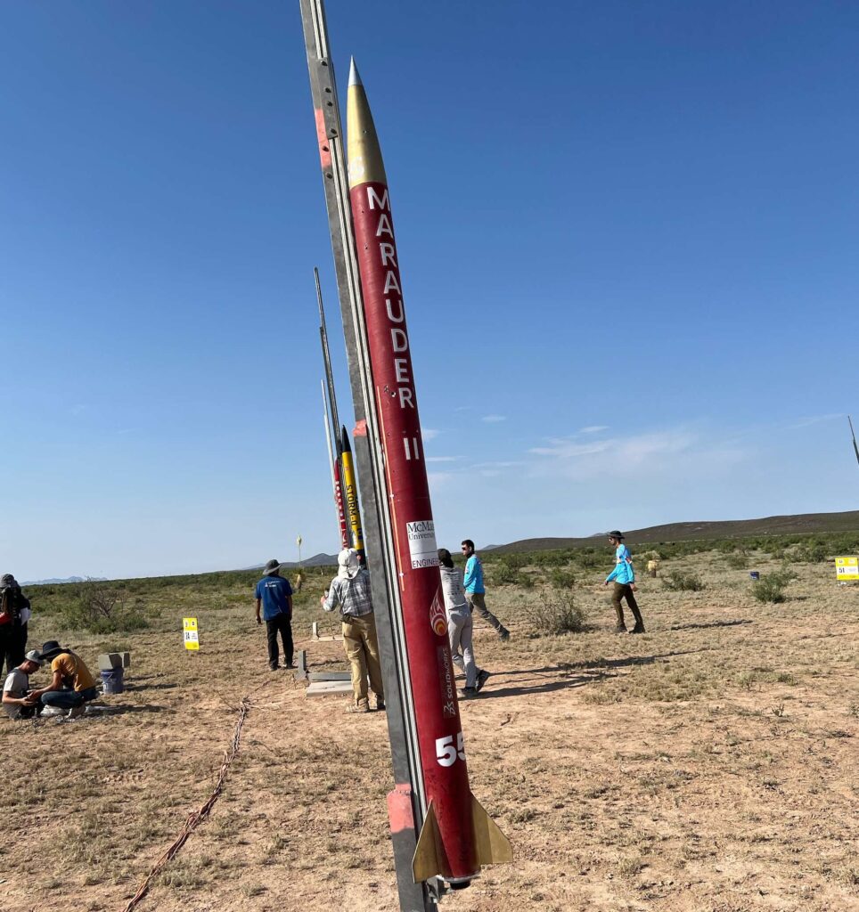 a rocket standing upright in the desert.