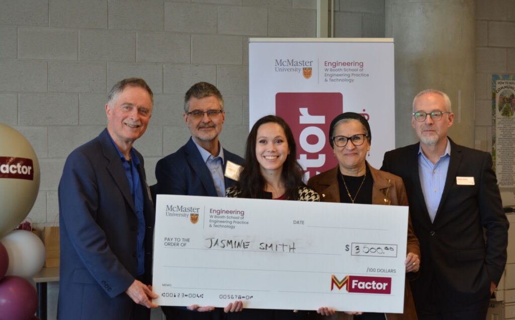five people posing together holding up a large check.