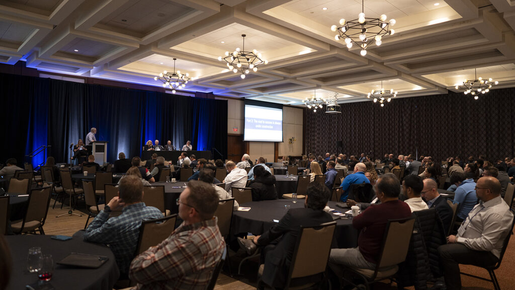 Conference delegates sitting around tables in a ballroom.