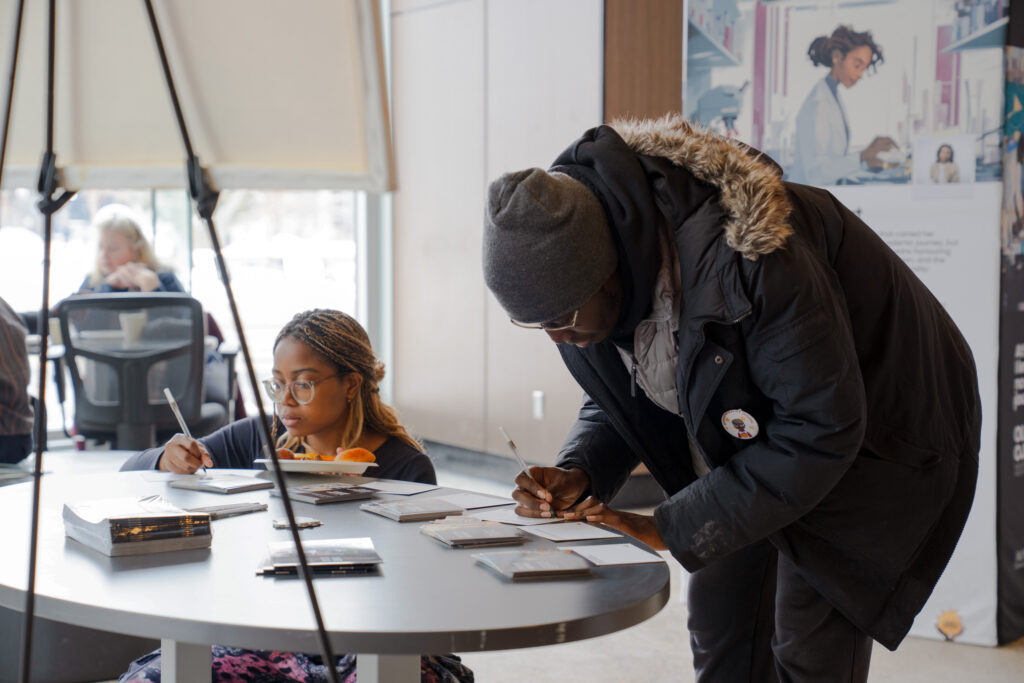 Students filling out reflection cards at the rooted beings exhibition