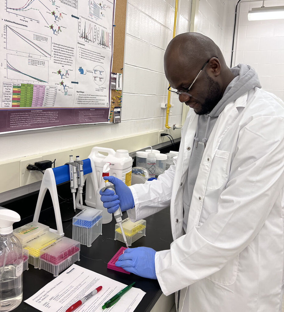 Albert Ashong with his head down working with lab instruments