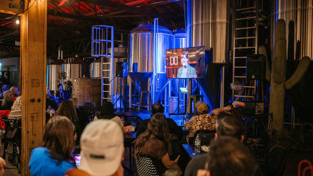 The screen showing CBC's Dragons' Den at the watch party with guests lookign on