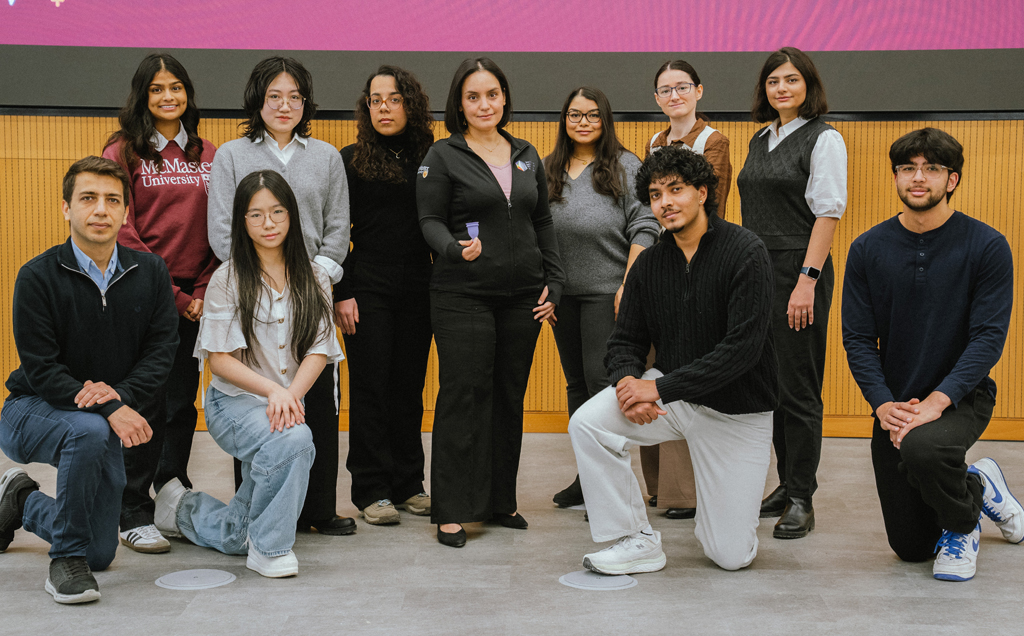 Zeinab is surrounded by her graduate students, some on their knees in front, and she holds out a purple BFree menstrual cup