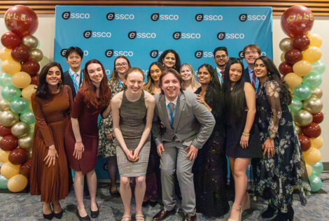 A group of people smiling in front of a backdrop