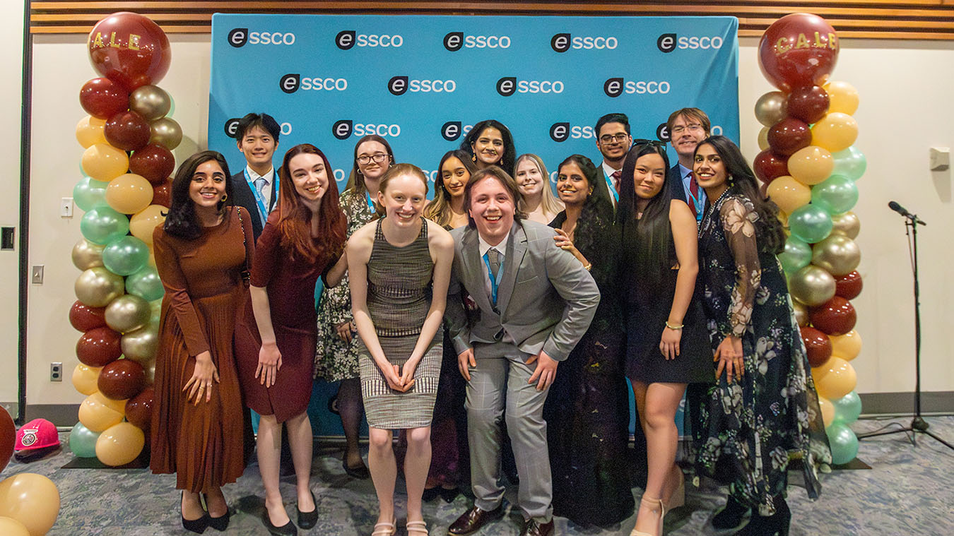 A group of people smiling in front of a backdrop