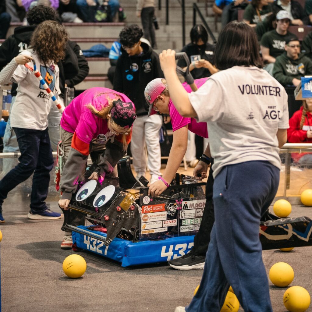team members are fixing a robot on the field