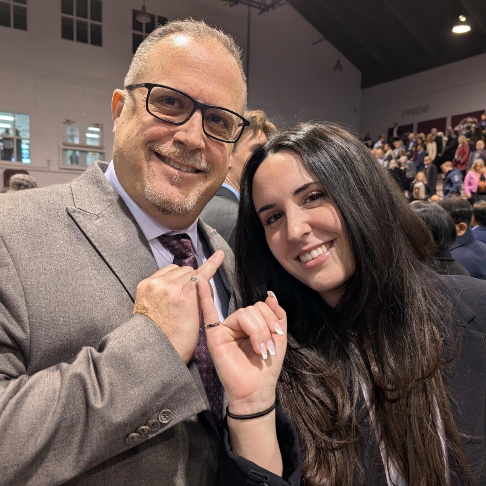 Rebecca and Angelo hold their pinkies up together showing off their iron rings