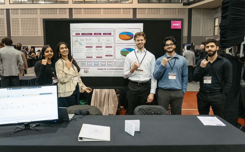 The Chemineers team pose in front of their capstone poster all holding their iron ring pinkies up
