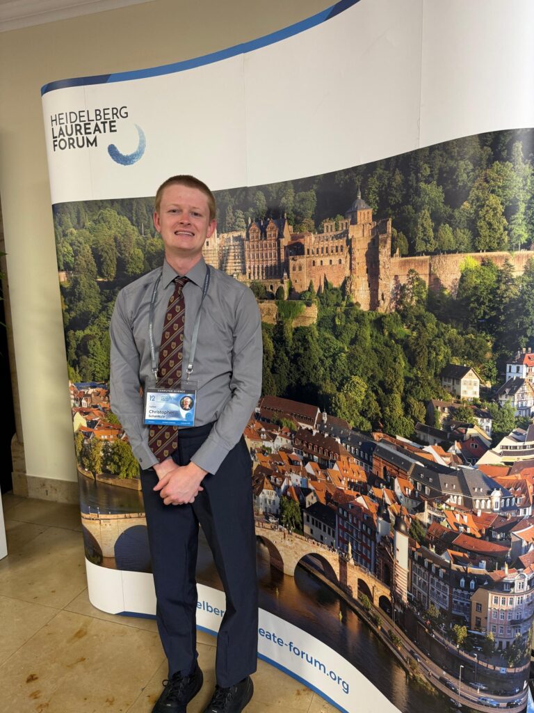Chris poses in front of a Heidelberg Laureate Forum banner
