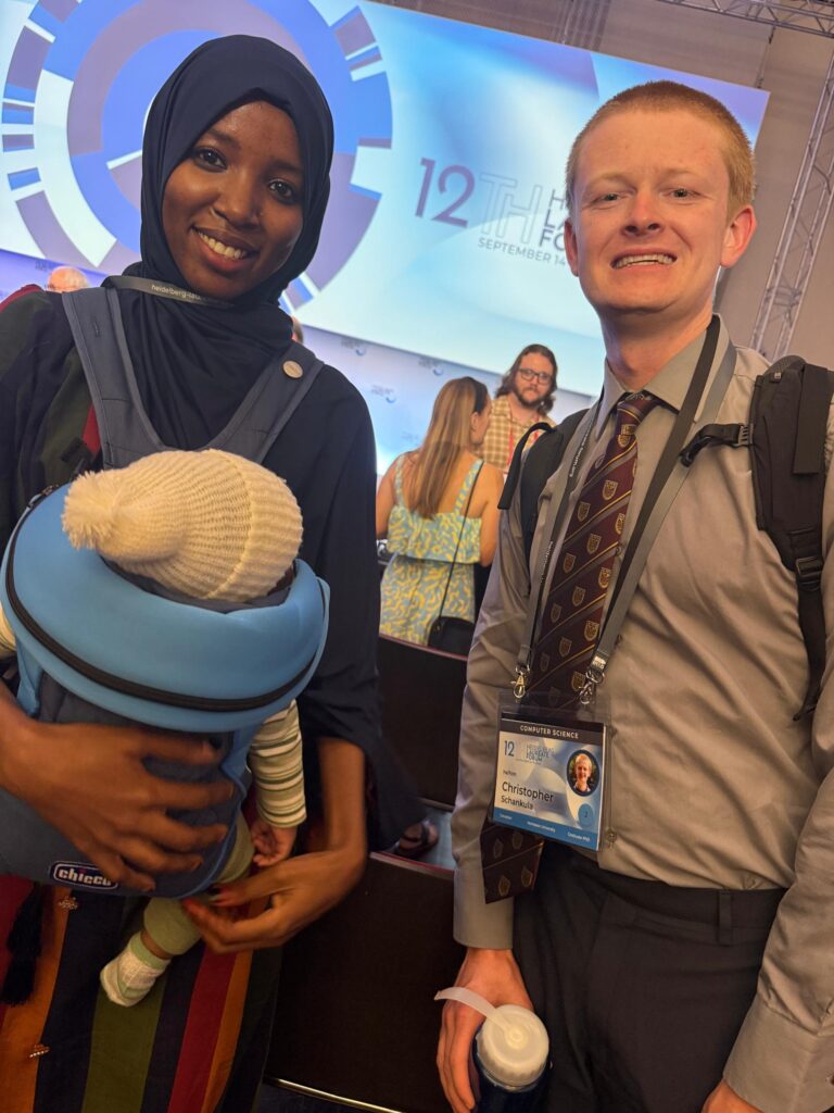 Chris poses with Halima who is wearing a child in a carrier