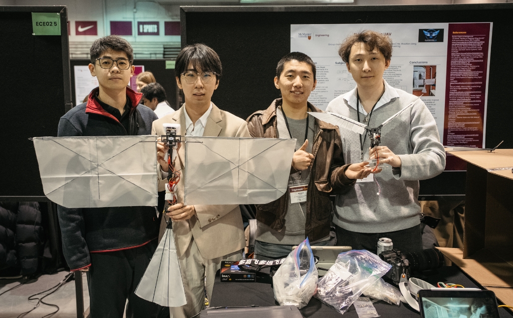 The team holds up their drone with wings