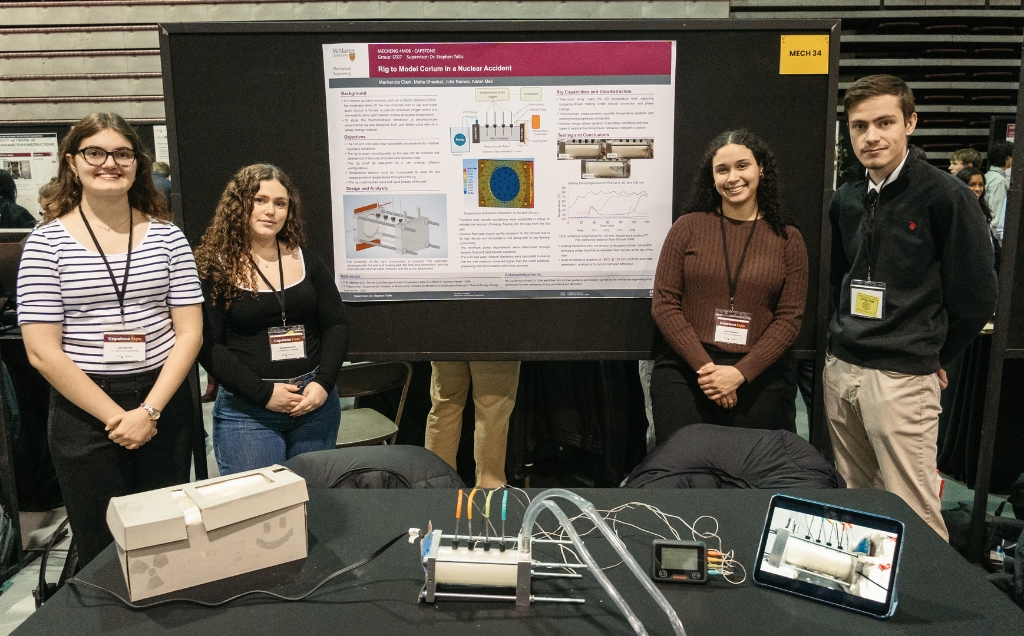 The team at their capstone booth with a prototype of the rig on their table