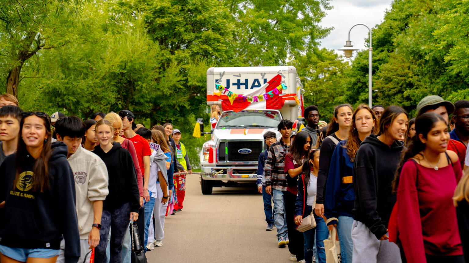 Group of McMaster Students pulling white bus.