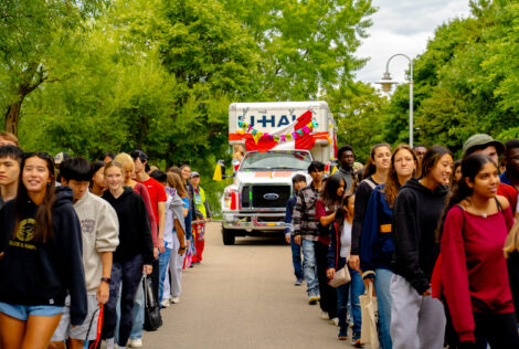 Group of McMaster Students pulling white bus.