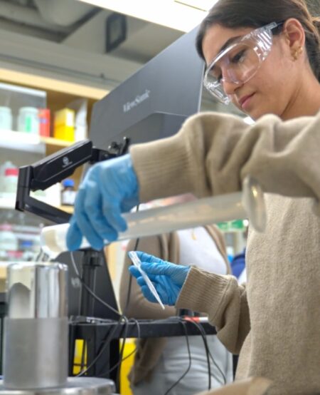 A student wearing safety glasses performs a chemical engineering experiment.