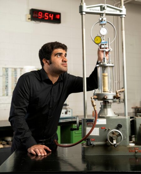 A student changes settings on a geotechnical machine.