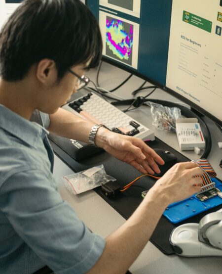 An over-the-shoulder shot of someone working with robotics and a computer.