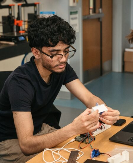 A person working at a desk examines electronic components.