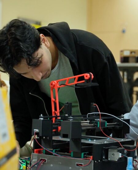 A student leans forward to examine an electrical engineering project.
