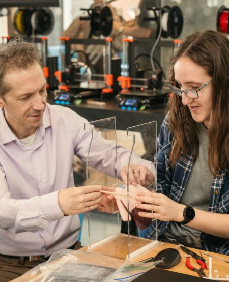 A professor helps a student construct a tabletop model of a closet.