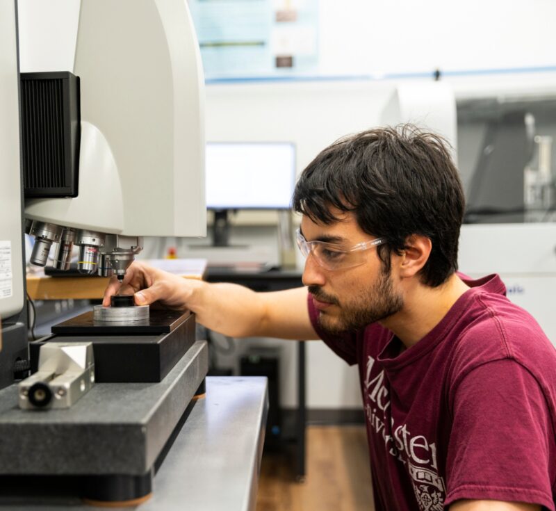 A person holds a sample under machinery in a lab.