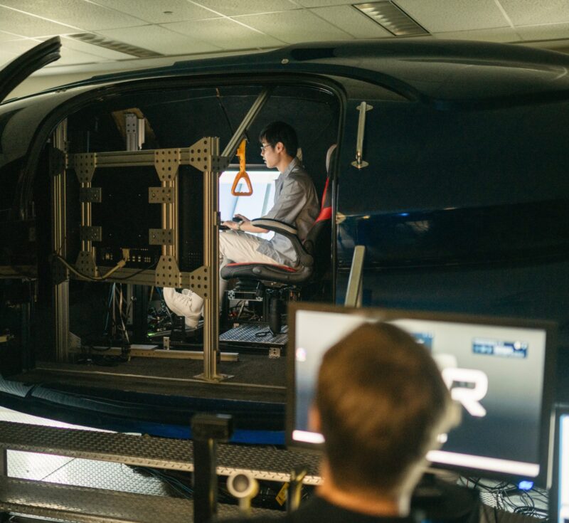 Someone sits in a simulator with the door open.