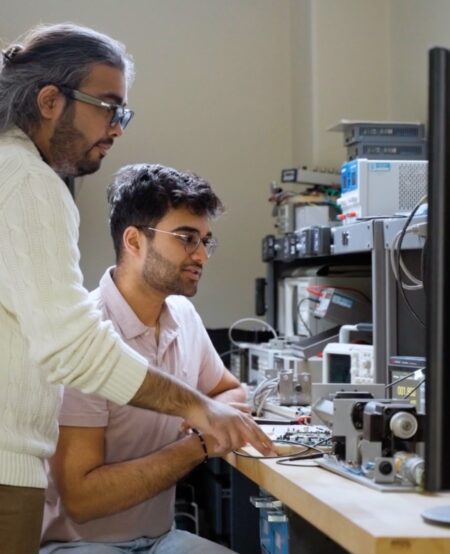 Two students look at machinery in a mechatronics lab.