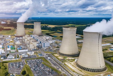 An aerial image from a distance of the countryside around a nuclear power plant and its four smokestacks.