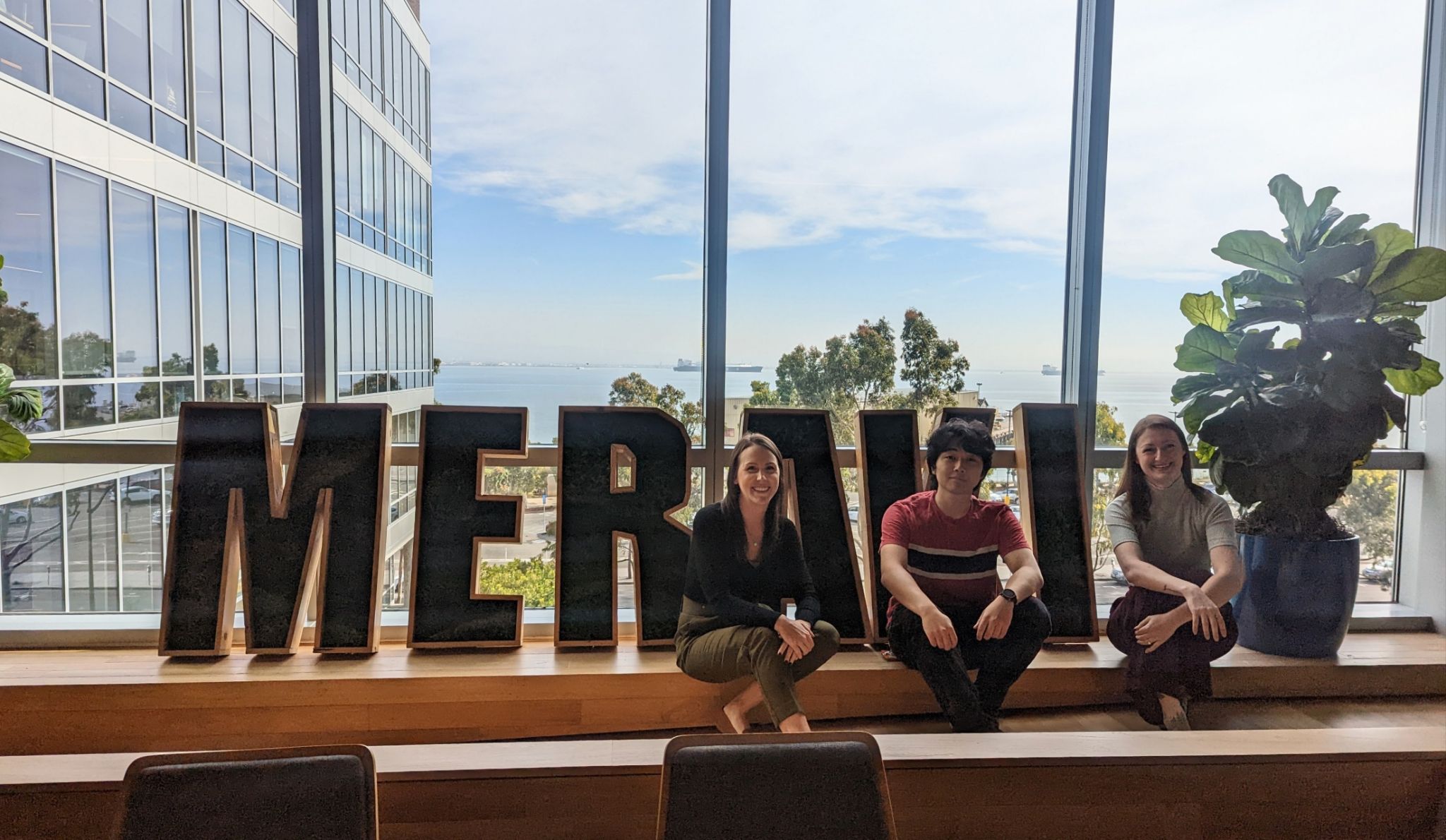 Megan Donogue (left), and Rachelle Ireson (right) of McMaster ECCS sit in front of a window with the Cisco Meraki sign with Calvin Suan (middle), Mechatronics co-op student
