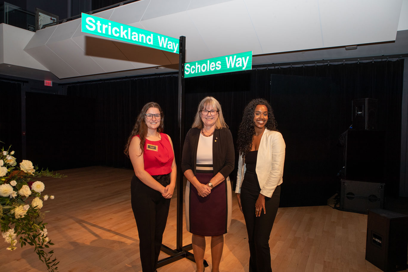 Donna Strickland stands with Shayna Earle and Mosana Abraha under the Strickland Way and Scholes Way street signs