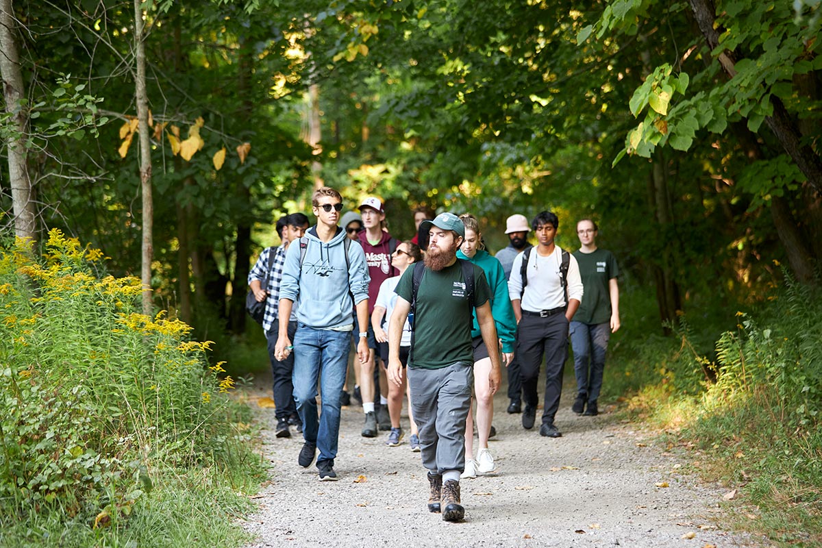 Noah leads a group of students on a hike through a path
