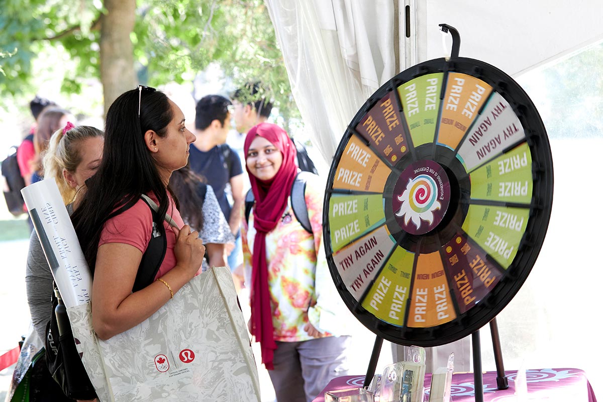 A women spins the prize wheel (another woman in the background has noticed the photo is being taken and has leaned in with a big smile on her face)