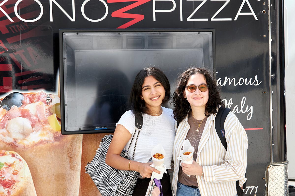 Two woman stand in front of Kono Pizza Cones truck