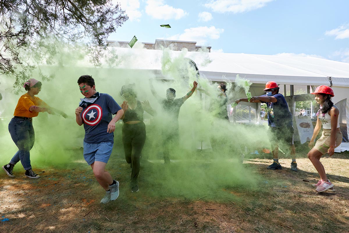 a group of students runs through a cloud of green chalk