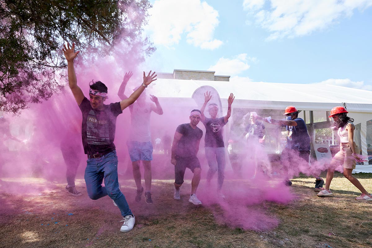 a group of students runs through a cloud of purple chalk